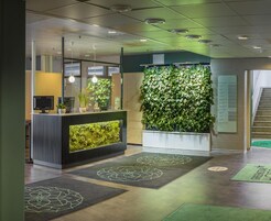 A reception area with a green wall, a reception desk, and a staircase.