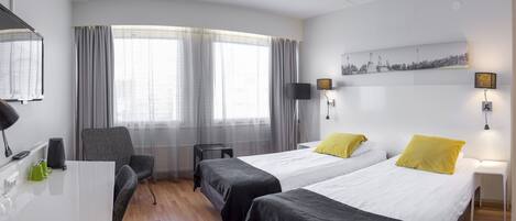 Una habitación de hotel con dos camas, un escritorio, una silla, un televisor y un cuadro en la pared.