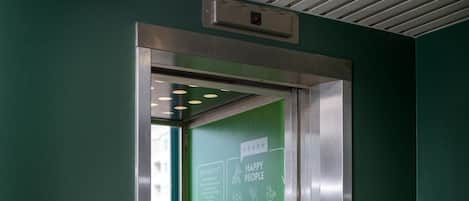An elevator with a green interior and a sign promoting sustainability.