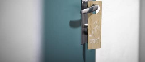 Una puerta con una cerradura moderna y una placa de madera con el texto "GREENSTAN HOTEL".