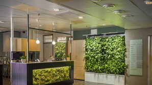 A reception area with a green wall, a reception desk, and a directory sign. - GreenStar Hotel Lahti (Lahti)