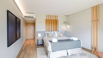 A modern bedroom with a large bed, a bedside table with a lamp, a wall-mounted air conditioner, and a wooden panel wall.