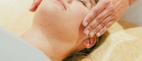 A person lying on a bed receiving a facial treatment.