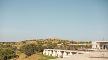 Un bâtiment moderne doté d’une terrasse offrant une vue sur un paysage vallonné.