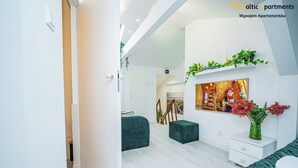 Una sala de estar moderna con un sofá, un reposapiés y una pequeña mesa blanca con un florero.