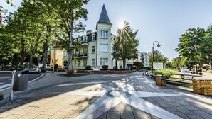 Un hotel con techo a dos aguas, una zona peatonal empedrada y una bicicleta aparcada cerca.
