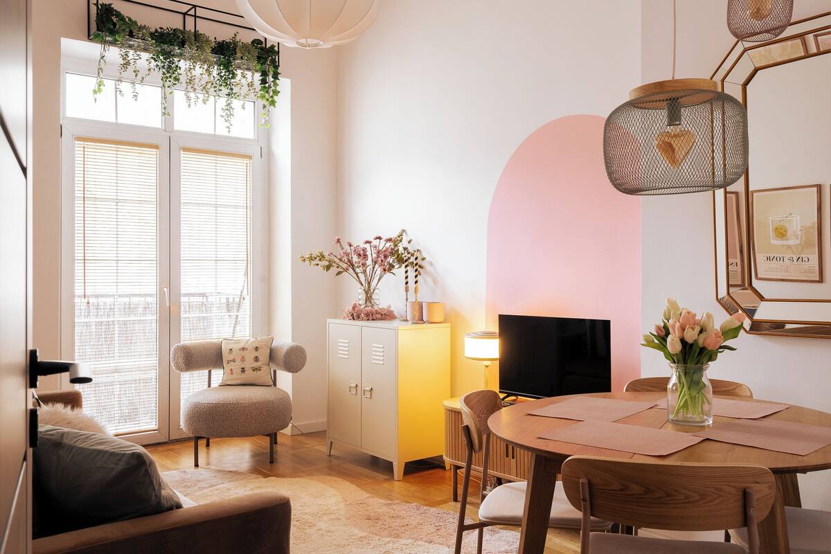 Un salon confortable avec un canapé, une table à manger et des chaises, un téléviseur et un meuble contenant des objets décoratifs.