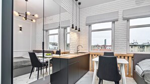 A modern kitchen with a central island, black chairs, and a large window with a city view. - RentPlanet - Apartamenty Ruska (Wroclaw)