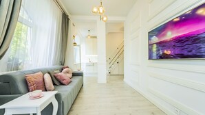 A modern living room with a grey sofa, a white coffee table, and a large TV on the wall. - Baltic Apartments-Willa Carmen 14 (Swinoujscie)