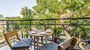 A balcony with two wooden chairs and a small round table set with plates, cups, and a glass. - Baltic Apartments-Willa Carmen 14 (Swinoujscie)