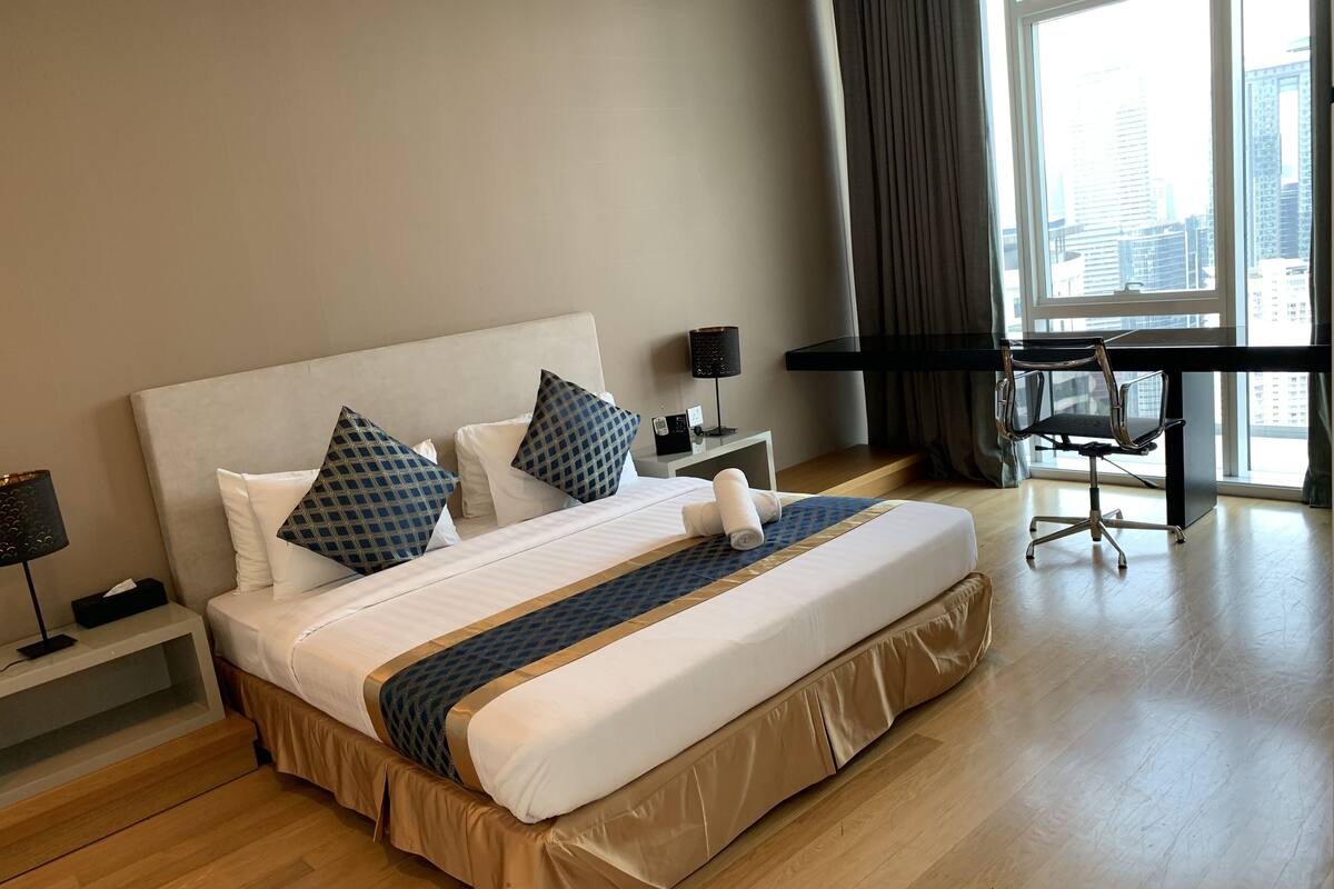 A hotel room with a large bed, a desk, and a chair.