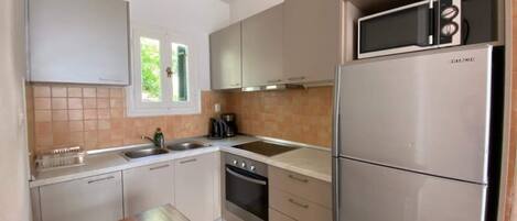 A modern kitchen with stainless steel appliances, white cabinetry, and a wooden dining table.