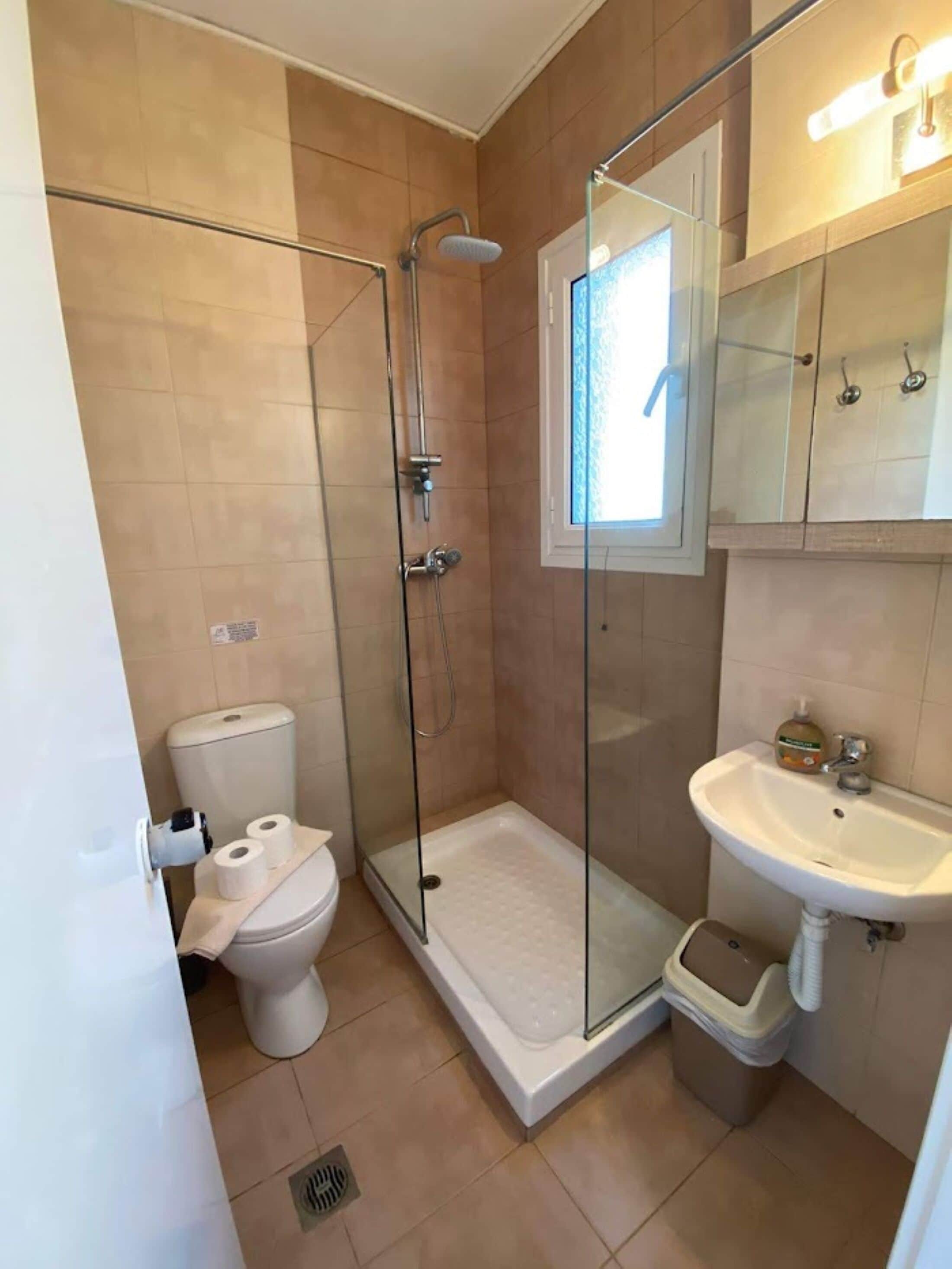 Ein Badezimmer mit Duschkabine, Toilette, Waschbecken und Fenster.