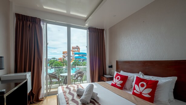 A hotel room with a bed, a desk, and a view of a water park. - Ban-aw Candon (Candon)