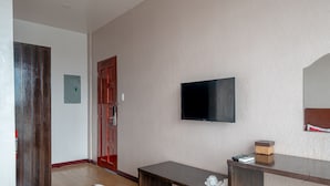 A room with a flat-screen TV mounted on the wall, a wooden door, a small table with a cup and saucer, and a bench. - Ban-aw Candon (Candon)