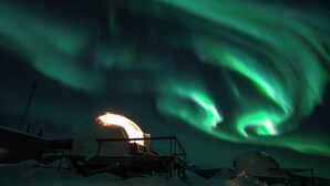 Ett snötäckt utomhusområde med en stor, sfärisk konstruktion och en mindre, kupolformad konstruktion, båda omgivna av snövallar.