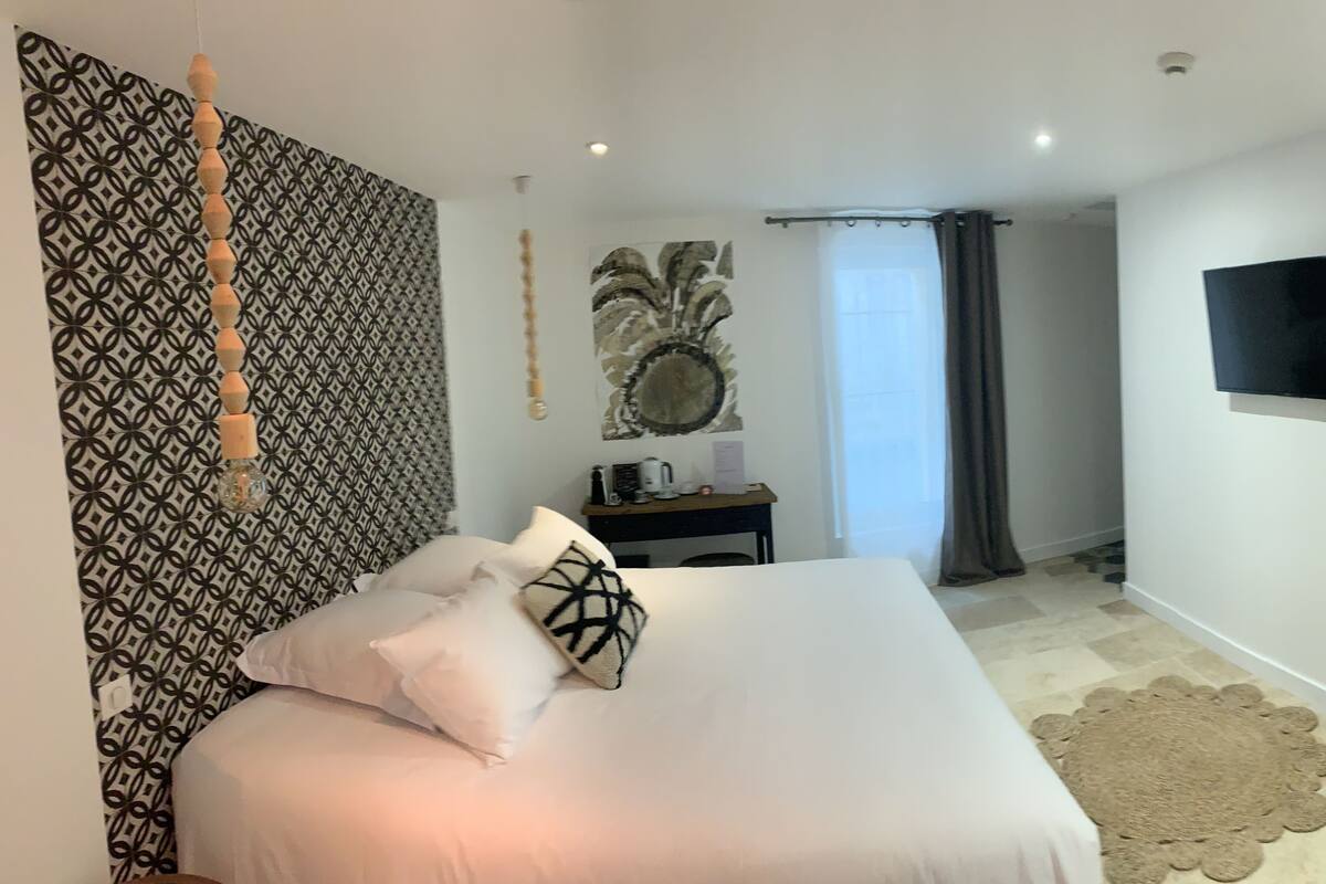 Un dormitorio con cama, televisor, escritorio y pared con diseño.