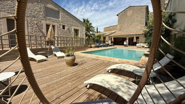 Une terrasse en bois avec des chaises longues et une piscine.