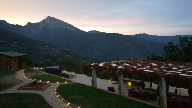 A mountainous landscape with a patio area featuring outdoor seating and a pathway lined with lights. - Agriturismo Al Pagan (Pigna)