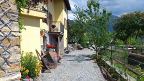 A building with a stone facade, a gravel path, and a wooden fence. - Agriturismo Al Pagan (Pigna)