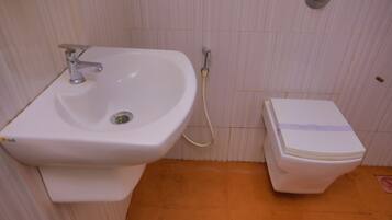 A bathroom with a sink, toilet, and a shower hose.