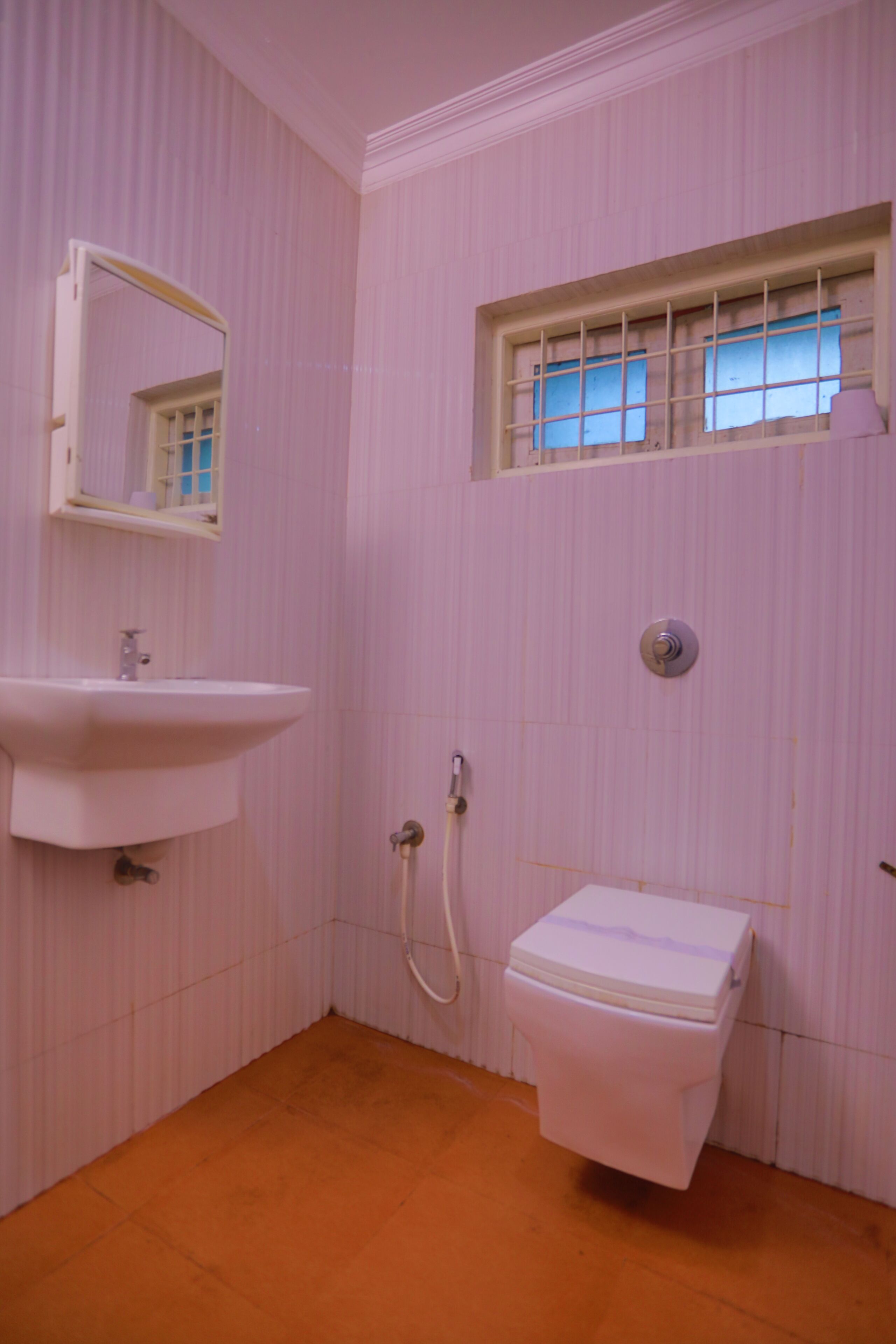 Een badkamer met een wastafel, spiegel, raam en toilet.