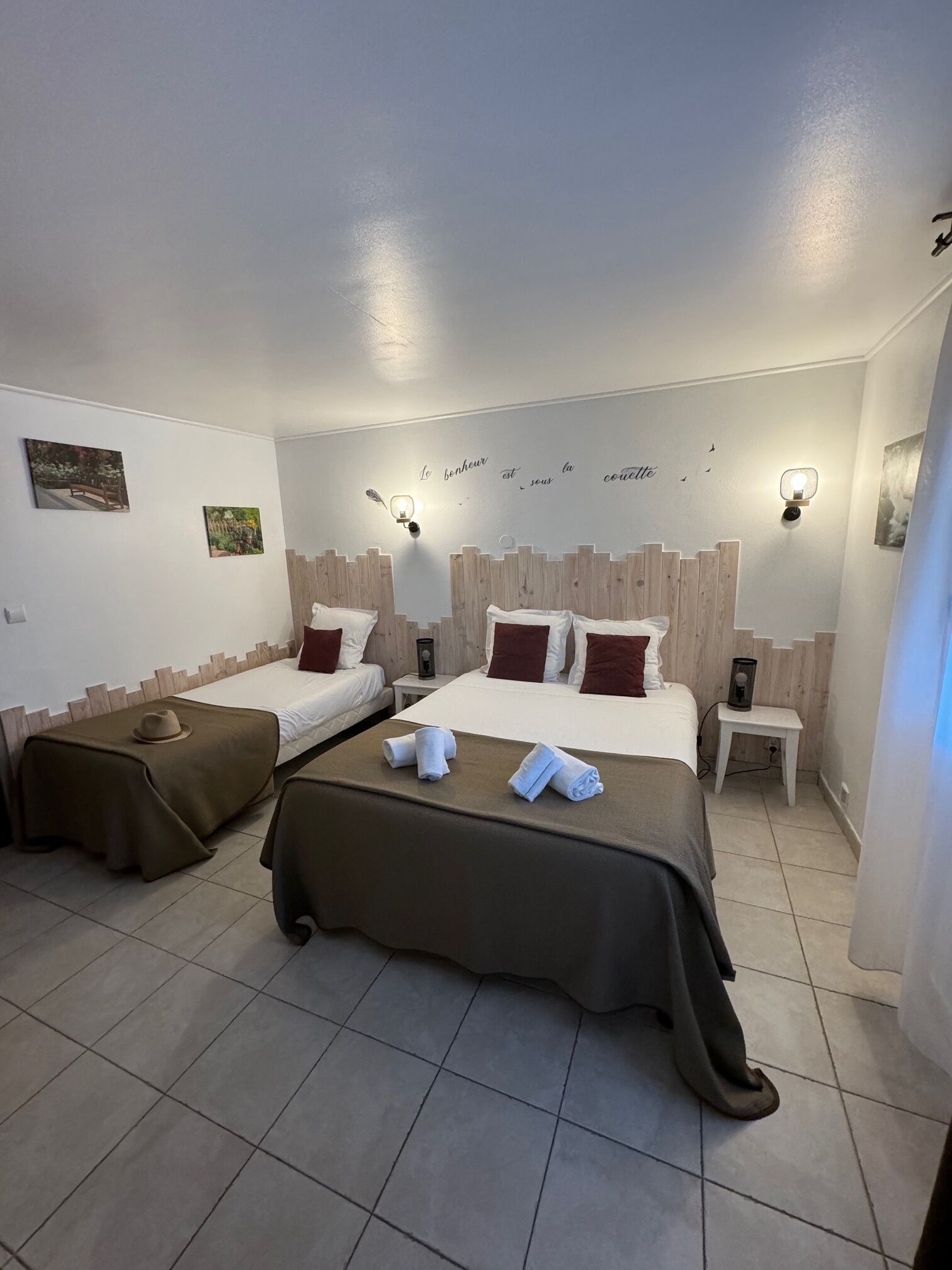 Una camera d'albergo con due letti, un tavolino e una parete con un lampadario decorativo.