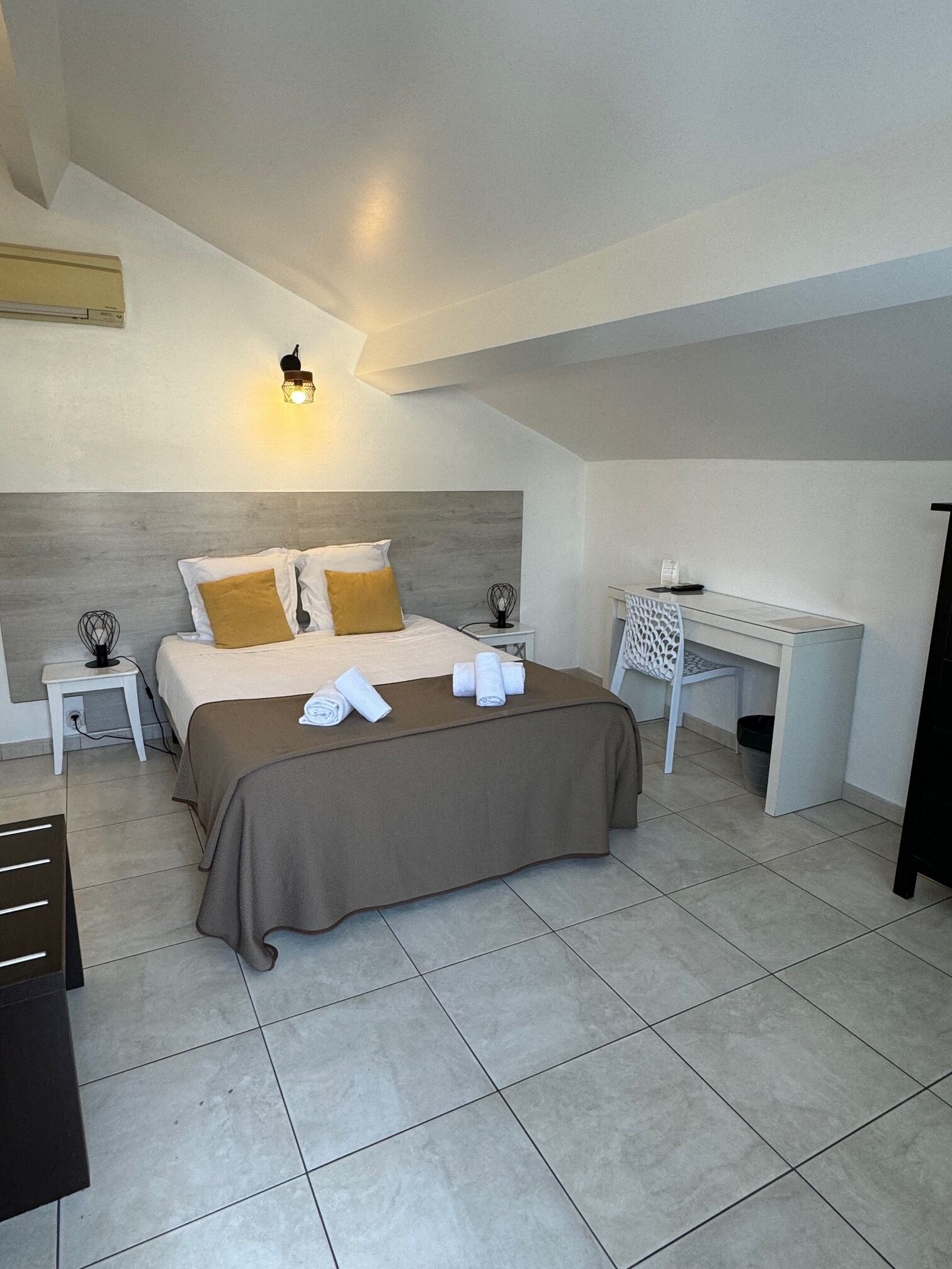 Een moderne hotelkamer met een groot bed, een bureau en een bijzettafeltje.