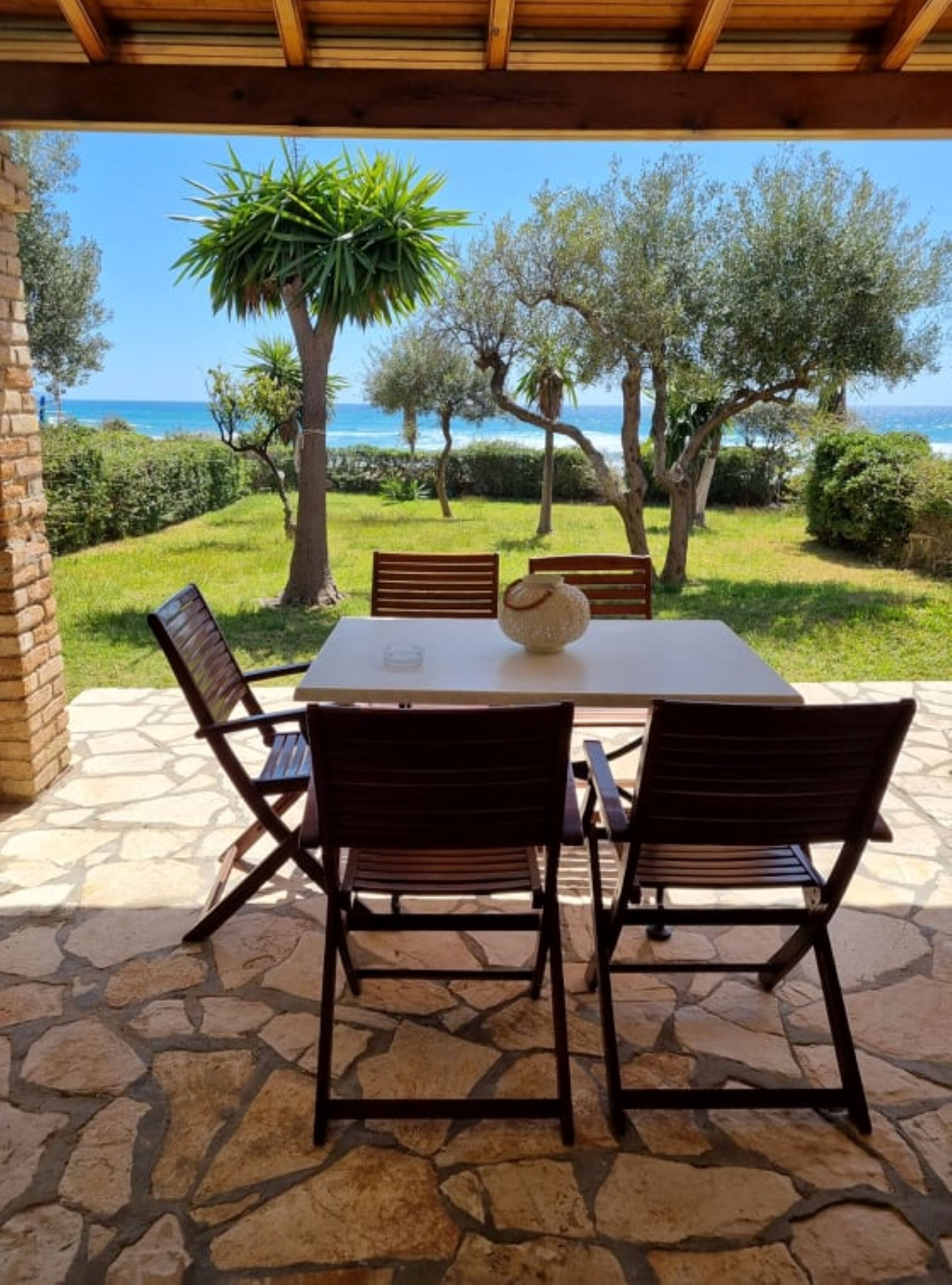 Un patio al aire libre con suelo de piedra, una mesa y cuatro sillas.