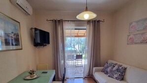 A small, cozy room with a dining table, chairs, a sofa, a TV, and a ceiling light. - Corfu Island Apartment 58 (Corfu)