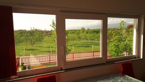 Ein Zimmer mit einem großen Fenster mit Blick auf ein grünes Feld und Bäume.