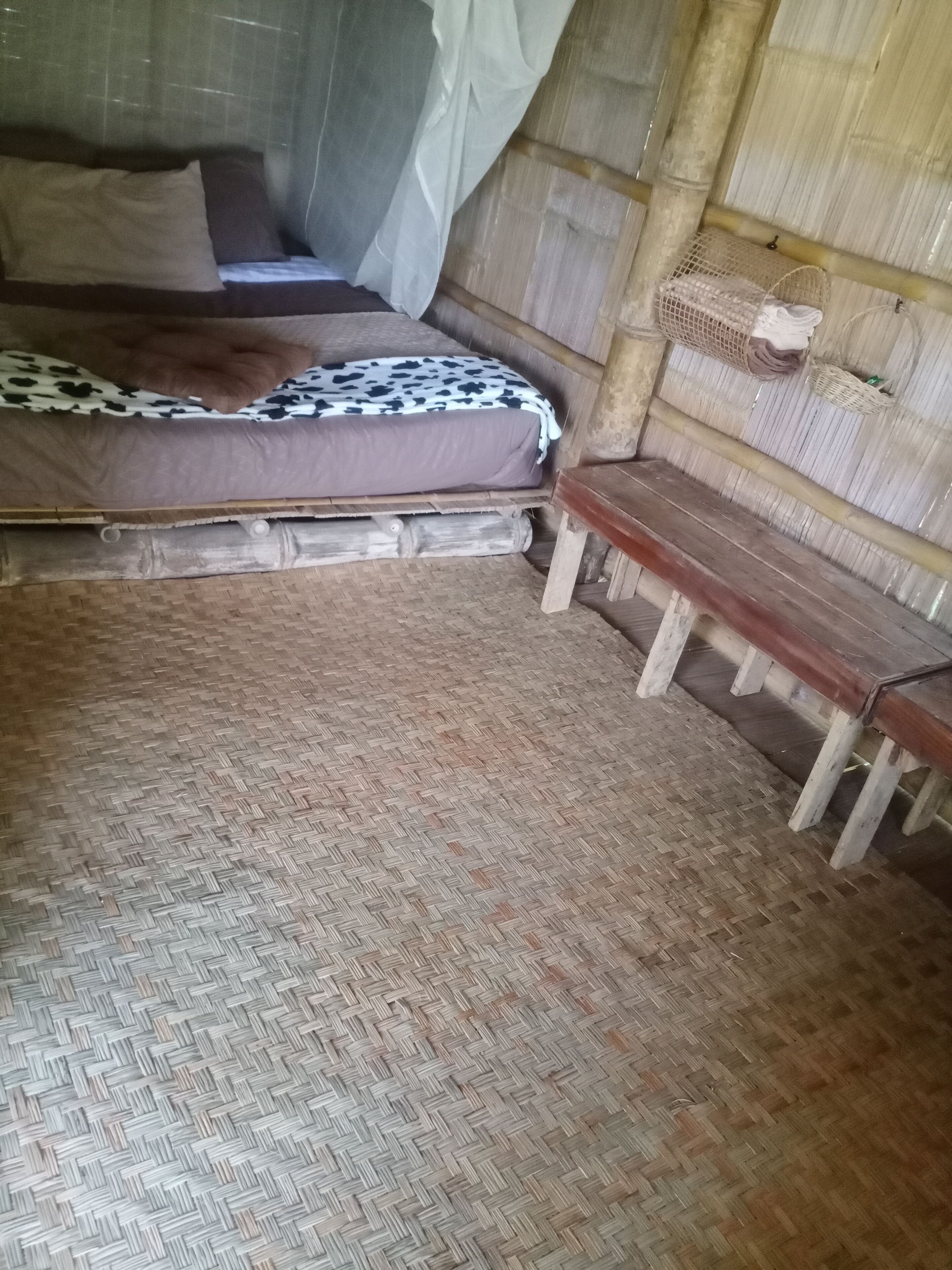 Une pièce avec un lit, un banc et un sol recouvert d’un tapis.