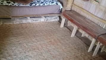 Une pièce avec un lit, un banc et un sol recouvert d’un tapis.