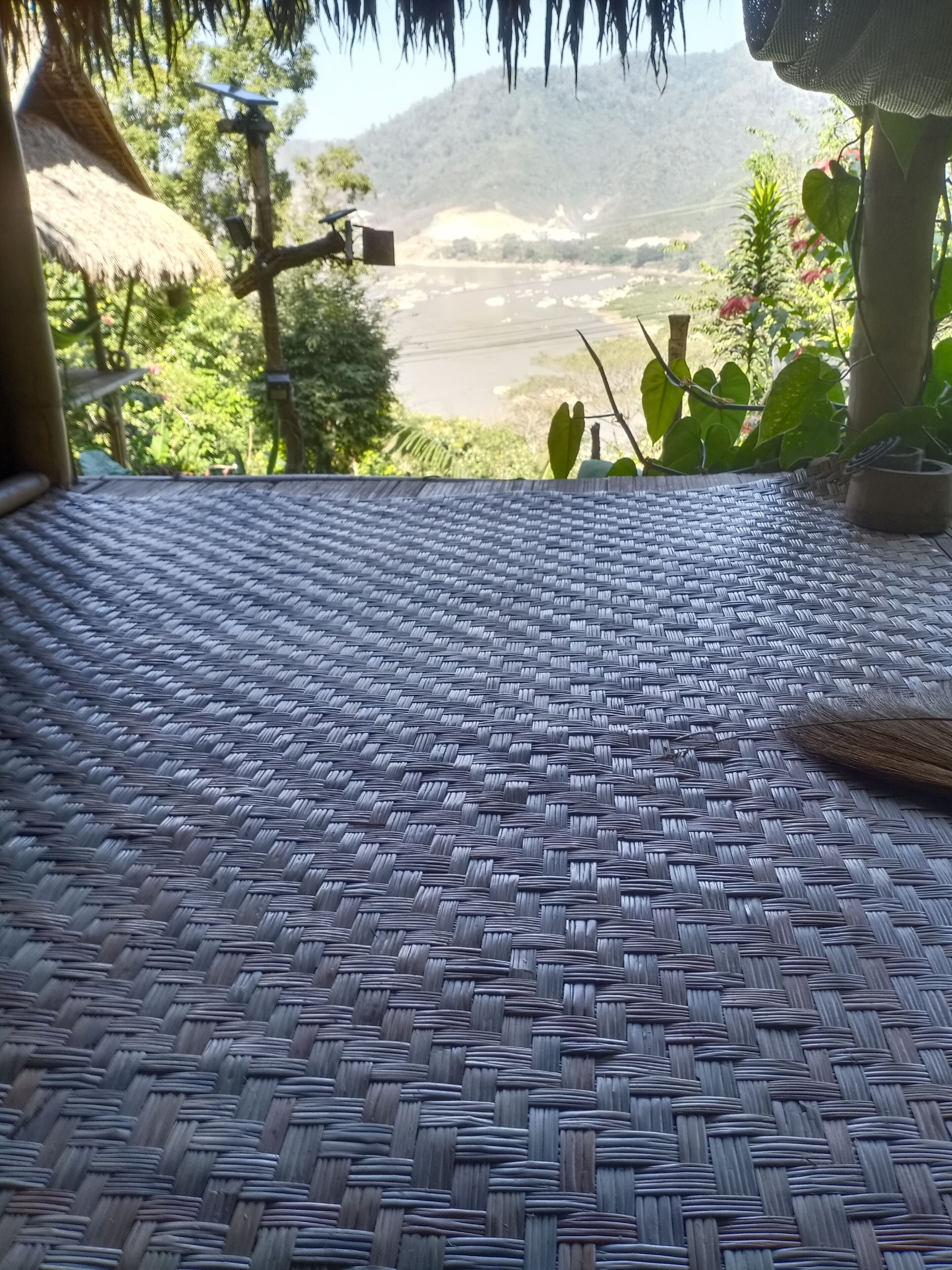 A woven mat floor with a view of a river and mountains in the background.