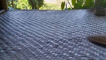 A woven mat floor with a view of a river and mountains in the background.