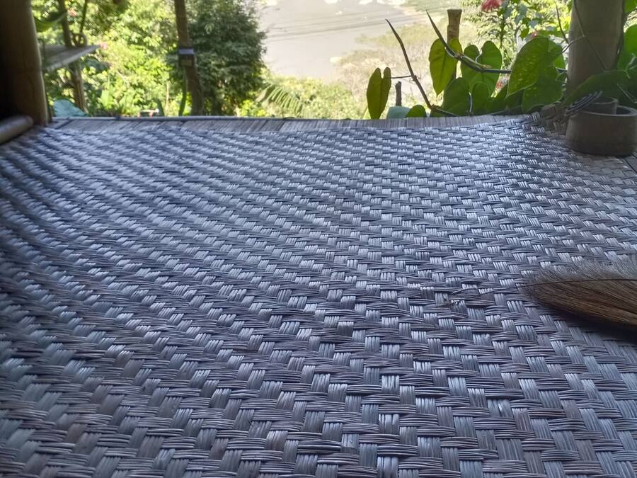 A woven mat floor with a view of a river and mountains in the background.