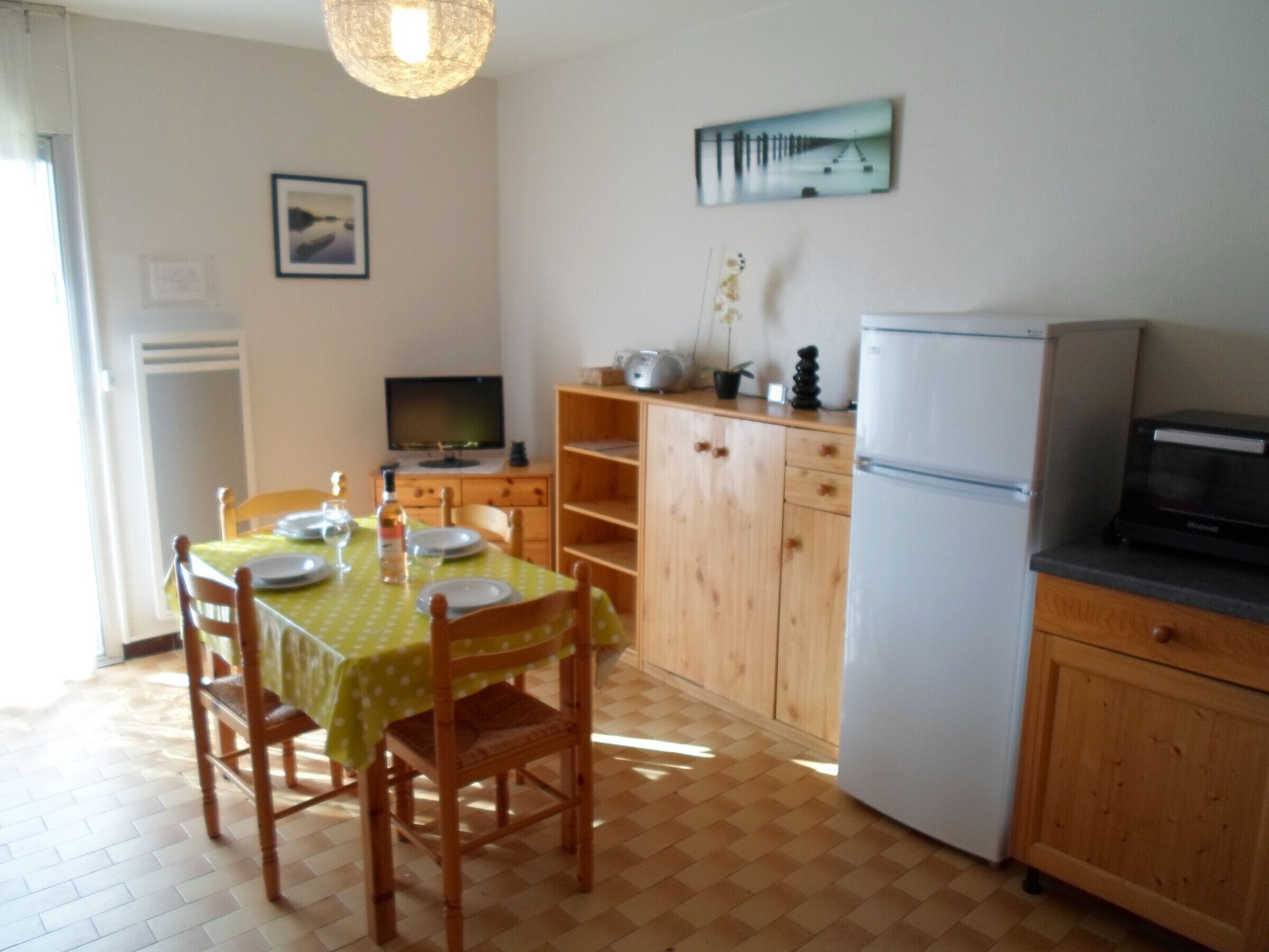 Une cuisine compacte avec des meubles en bois, une table à manger avec des chaises, un réfrigérateur et un four à micro-ondes.