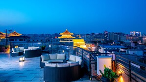 Une terrasse sur le toit, dotée d’un espace extérieur aménagé et offrant une vue sur un bâtiment traditionnel dont le toit est doré.