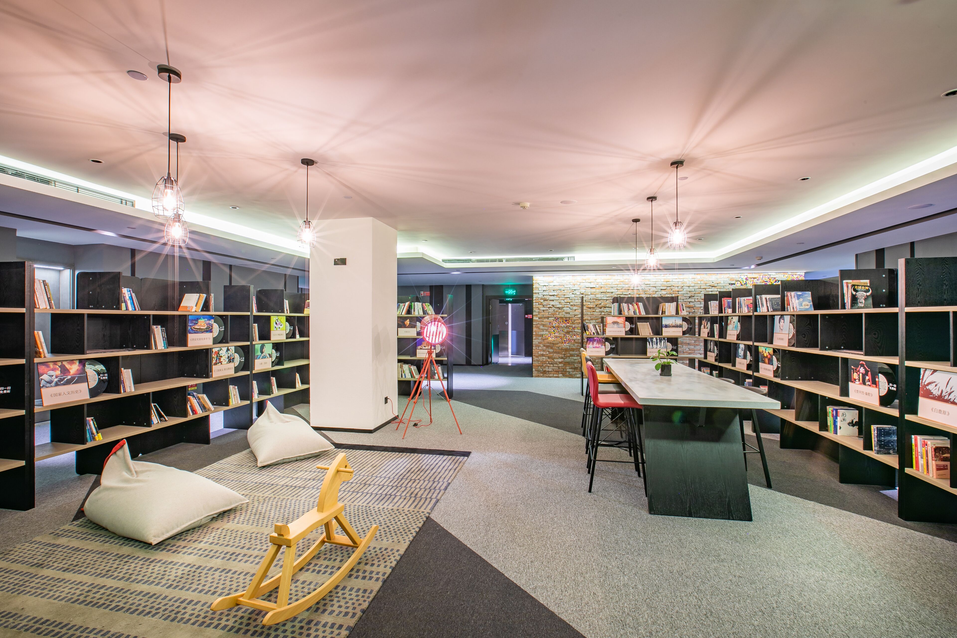 A modern library with bookshelves, a reading area, and a central table.