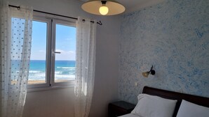 A bedroom with a bed, a nightstand, a wall clock, and a window with curtains.