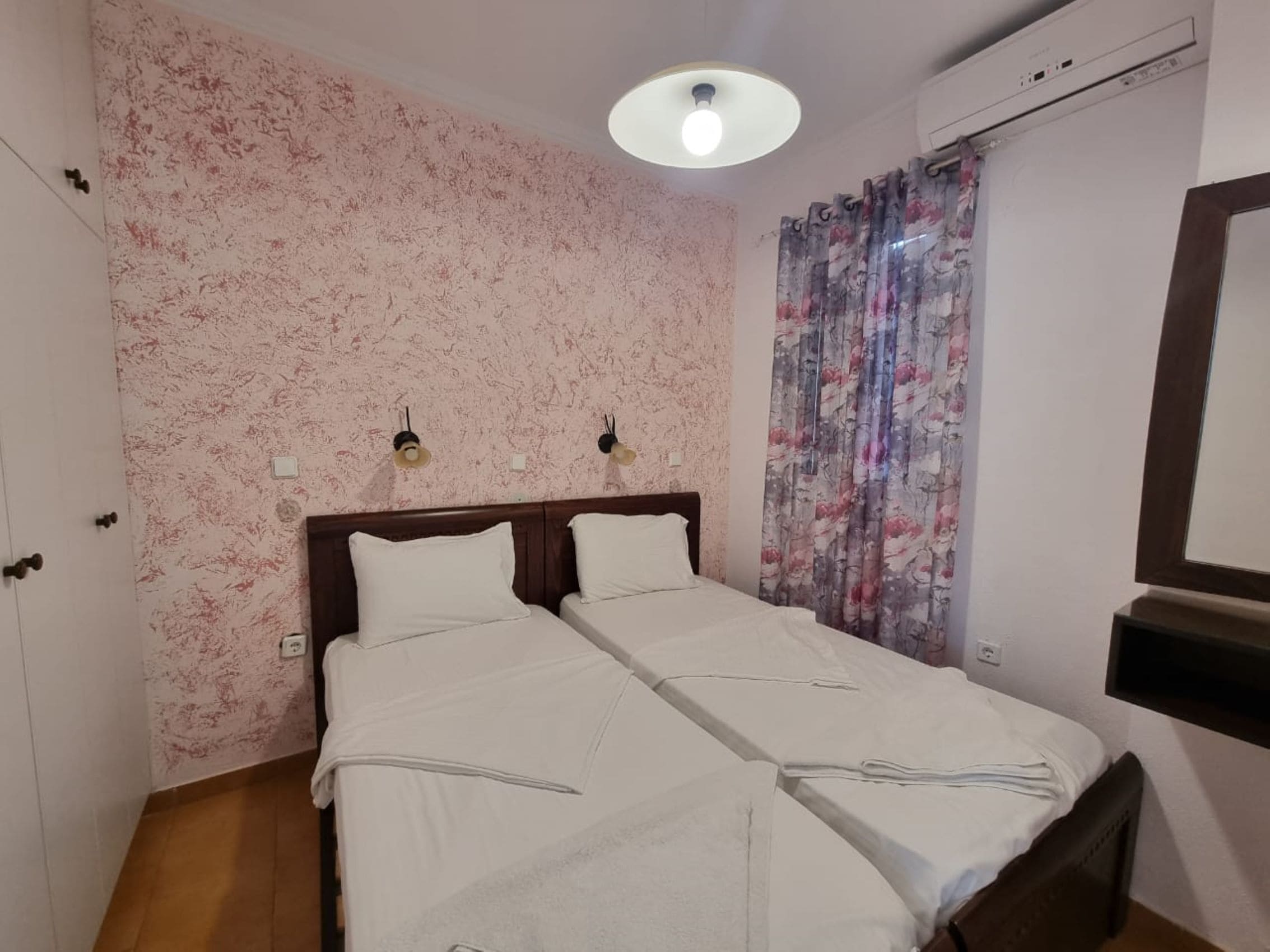Una cama doble con cabecera de madera, una lámpara de techo y una cortina con estampado floral.