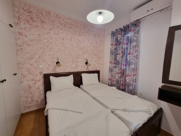 A double bed with a wooden headboard, a ceiling light, and a floral curtain. - Corfu Island Apartment 58a (Corfu)