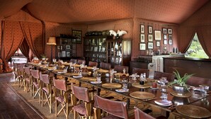 Un espace repas avec une longue table dressée pour accueillir plusieurs convives, entourée de fauteuils en cuir.