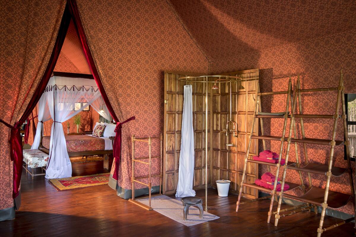 A room with a bed, a wooden wardrobe, a shelf unit, and a small stool.