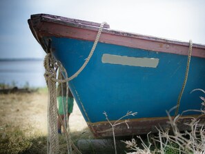 Um barco amarrado a um poste com uma corda, com estrutura azul e vermelha, e uma etiqueta branca na lateral.