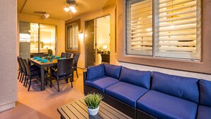 A patio area with a dining table, chairs, a blue sofa, and a ceiling fan. - Prime Location, Heated Pool, Fun Game Room, Putting Green, Outdoor BBQ, & More (Phoenix)