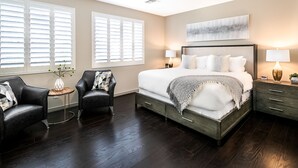 A bedroom with a large bed, two bedside tables, a chair, and a window with blinds. - Prime Location, Heated Pool, Fun Game Room, Putting Green, Outdoor BBQ, & More (Phoenix)