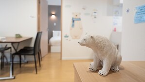 A polar bear figurine on a wooden table in a room with a dining area in the background. - The Peak Villa Suite Hokkaido (Higashikawa)