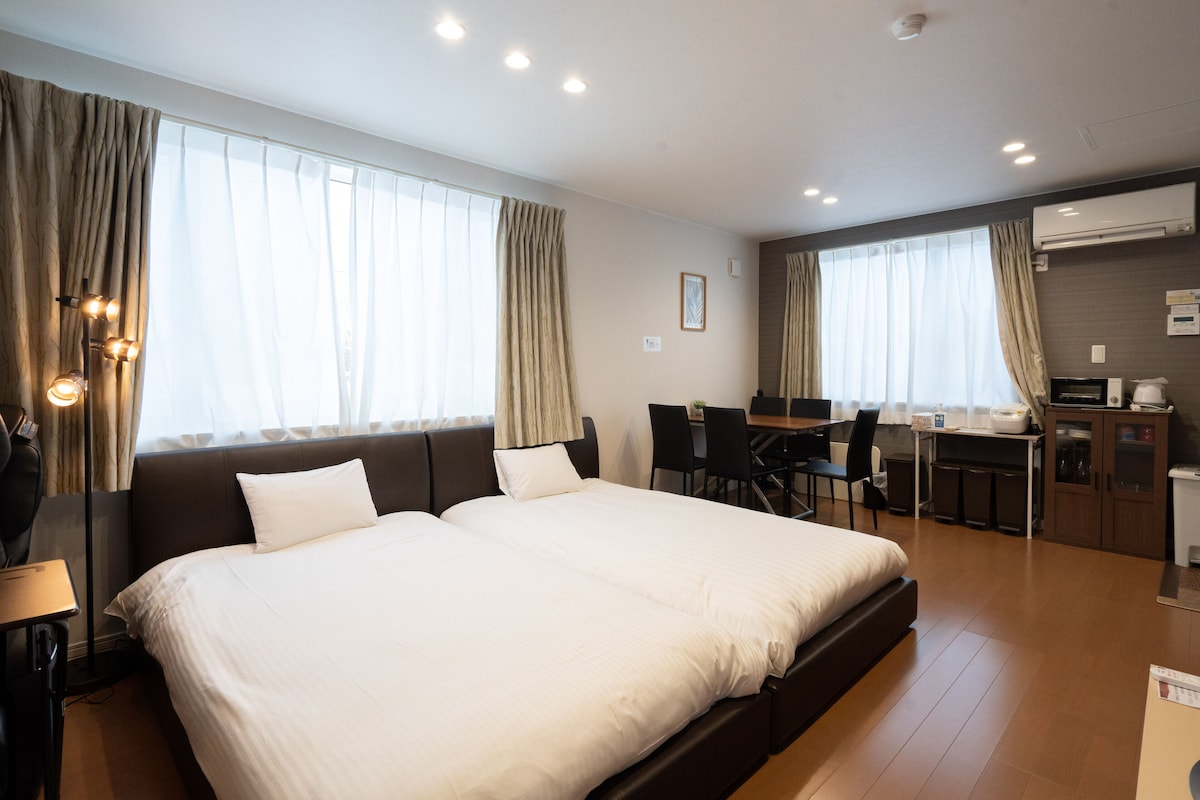 A hotel room with a large bed, a desk, and a kitchenette.