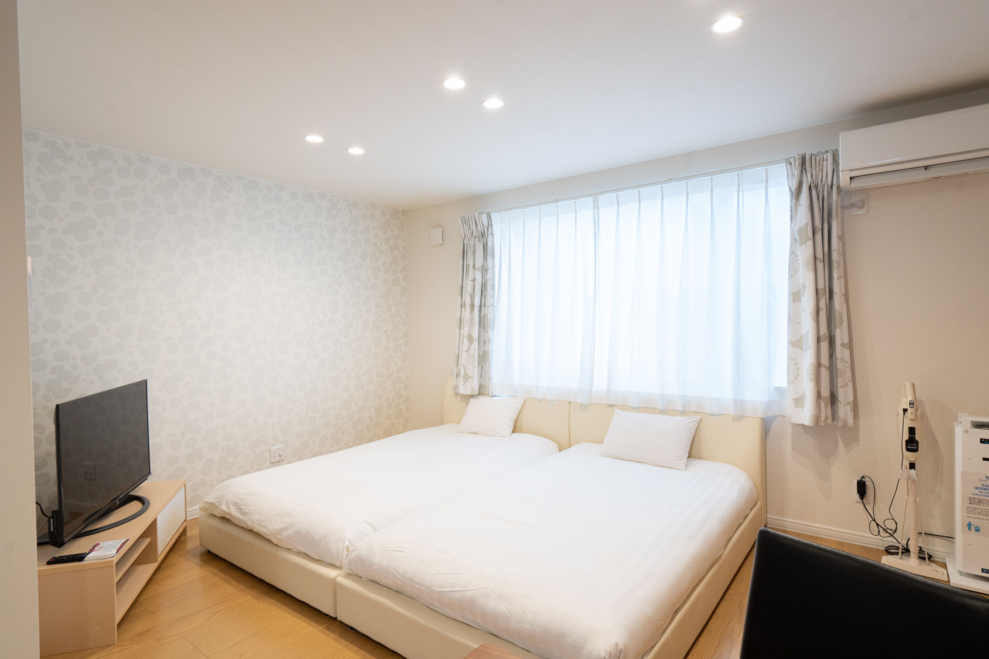 A modern hotel room with a large bed, a flat-screen TV, and a bedside table.